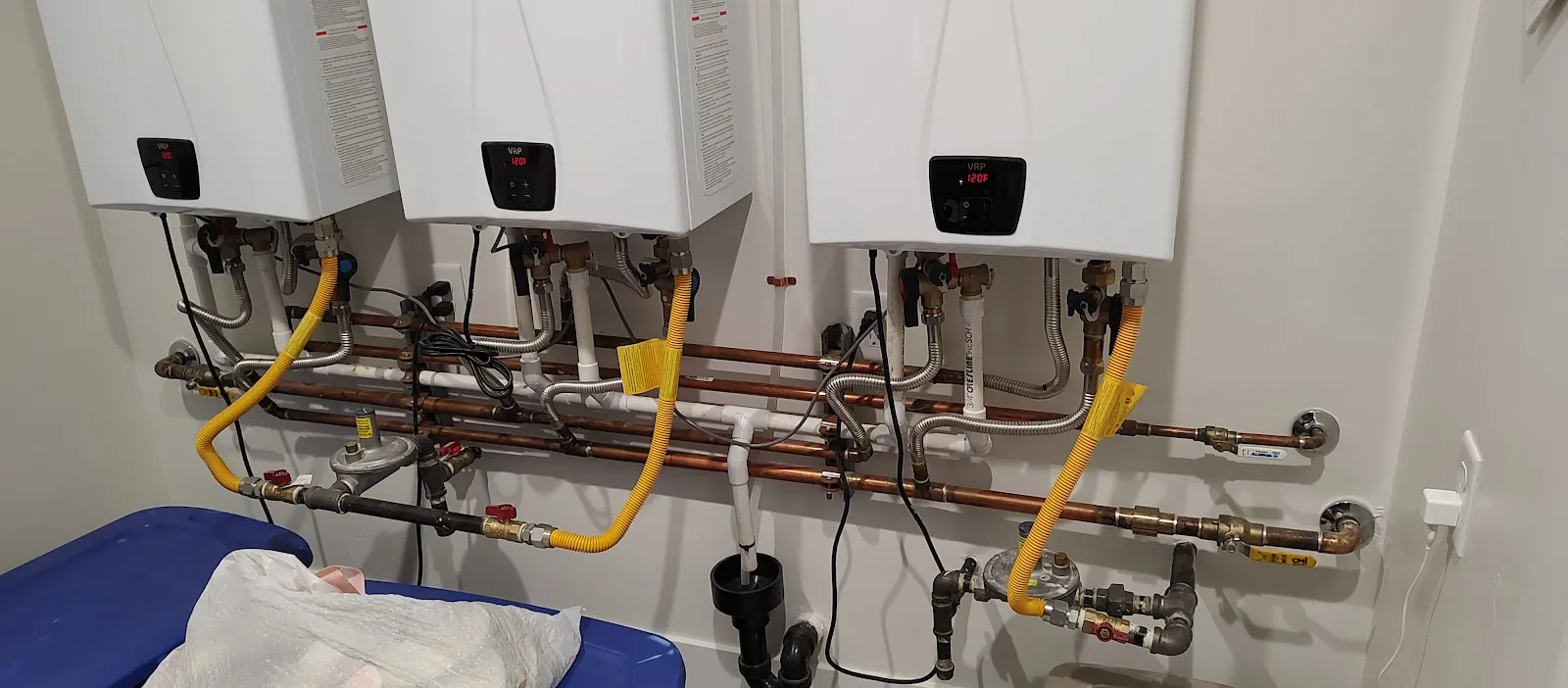 Three tankless water heaters installed in a row with new copper and gas lines