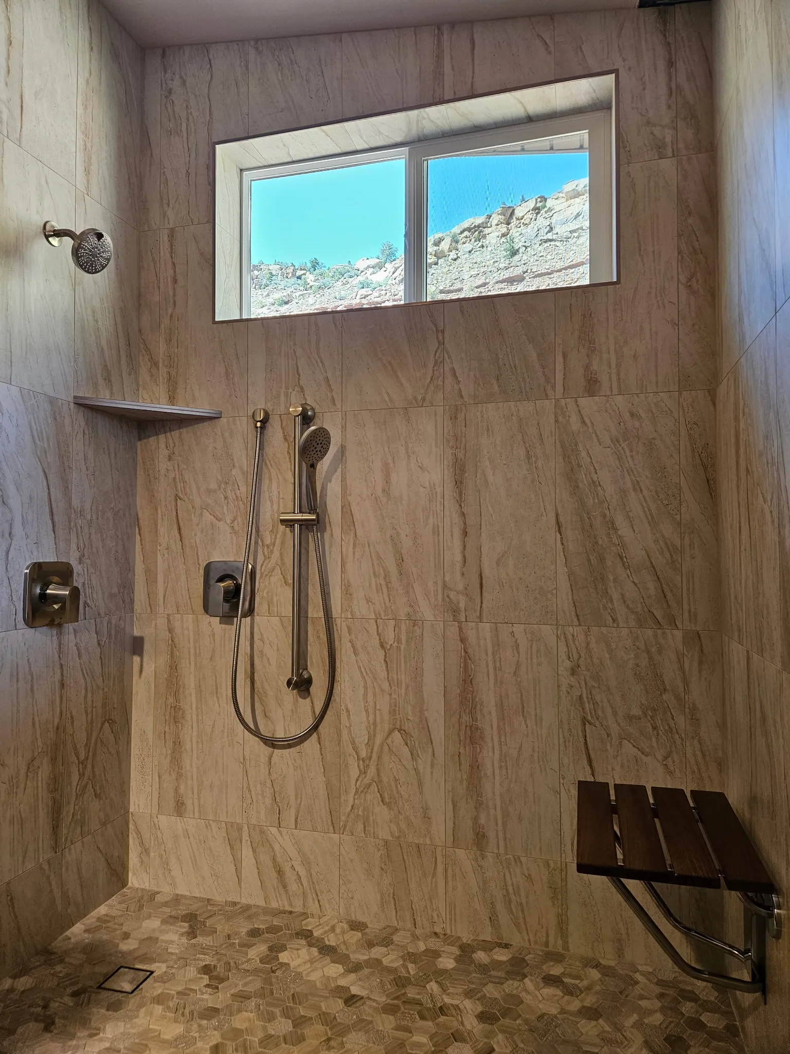 Custom tiled walk-in shower with new fixtures and a fold-down bench